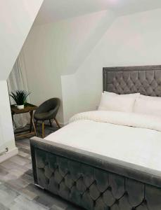 a bedroom with a large bed and a chair at Luxurious new built kingsize bedroom in Manchester