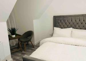 ein Schlafzimmer mit einem Bett, einem Stuhl und einem Tisch in der Unterkunft Luxurious new built kingsize bedroom in Manchester
