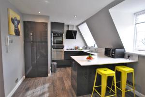 a kitchen with two yellow stools and a counter top at Executive Apartment in Central Windsor in Windsor