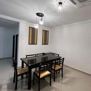 a dining room with a black table and chairs at Laena Homestay in Kangar
