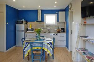 a kitchen with a table and a blue wall at Baie du Mont Saint Michel / Gîte de la Vaquerie 23 in Vains +6 photos