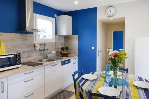 a kitchen with a table with chairs and a clock on the wall at Baie du Mont Saint Michel / Gîte de la Vaquerie 23 in Vains