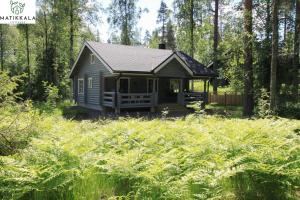 a small cabin in the middle of a field of grass at Matikkala Cottages in Ruokolahti