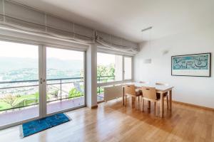 comedor con mesa, sillas y ventanas grandes en Aldesago City View by Quokka 360 - flat with a breathtaking view, en Viganello