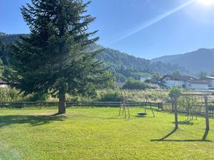 a park with a tree and swings in the grass at LYMA Suites - Studio S70 in Immenstadt im Allgäu