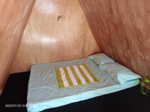 Bett in einem Zimmer mit einer Holzwand in der Unterkunft Croods farm house in Kodaikanal