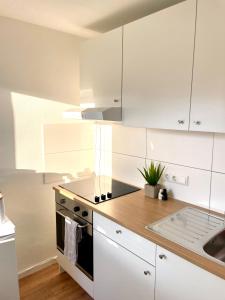 La cuisine est équipée de placards blancs, d'une cuisinière et d'un évier. dans l'établissement Stilvolle Wohnung im Herzen von Immenstadt - Nähe Mittag, Iller, Inselsee, à Immenstadt