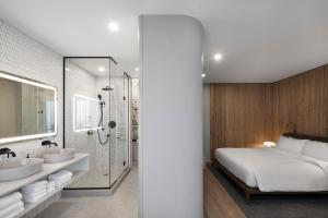 een slaapkamer met een bed, 2 wastafels en een douche bij Hôtel Le Germain Montréal in Montreal