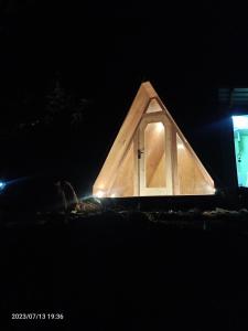 a dog is sitting in front of a triangular house at Croods farm house in Kodaikānāl