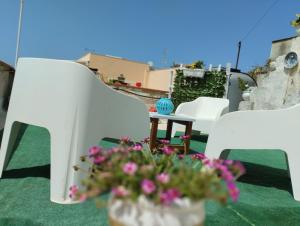 um grupo de cadeiras brancas e uma mesa com flores em Casa Vacanza San Vito Lo Capo em San Vito lo Capo