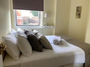 een bed met witte kussens en een raam bij 2 Bedroom Apartment in Central Windsor in Windsor