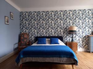 a bedroom with a blue bed and a wallpaper at Maison Violette en Berry in Aigurande