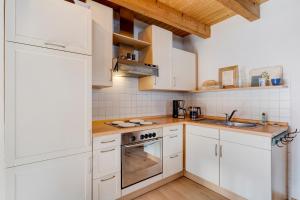 cocina con armarios blancos y fogones en Miris Hüs, en Endingen am Kaiserstuhl