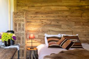 a bed in a room with a wooden wall at Cabin Margot with hot tub in private garden in Kaprijke