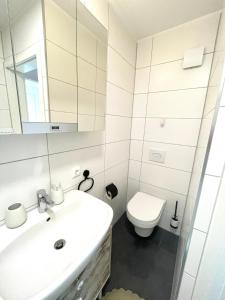 La salle de bains blanche est pourvue d'un lavabo et de toilettes. dans l'établissement Stilvolle Wohnung im Herzen von Immenstadt - Nähe Mittag, Iller, Inselsee, à Immenstadt