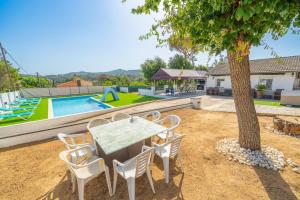 una mesa y sillas junto a un árbol en un patio en HomeHolidaysRentals Adaggio - Costa Barcelona, en Fogars de la Selva