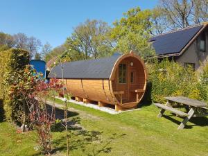 a circular wooden cabin in a garden with a picnic table at Barrel in Oostvoorne in Oostvoorne