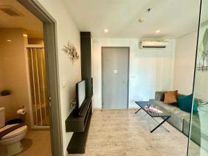 a living room with a couch and a television at Best Location Condo with swimming pool, gym, sauna, washing mashine, Fast internet in Central of Pattaya in Pattaya Central
