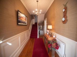 a hallway with a red carpet and stairs with a clock at Ceol na Mara Guest House in Enniscrone