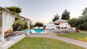 a backyard with a pool and chairs and an umbrella at Acrotel Athena Villa in Elia