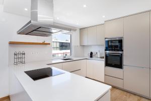 una cocina blanca con armarios blancos y fregadero en Luxury Beachfront 2 Bedroom's Penthouse - Mar do Sol By Centralgarve, en Quarteira