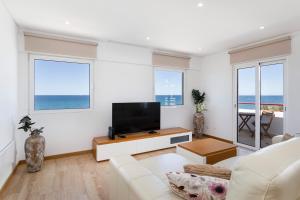a living room with a couch and a flat screen tv at Luxury Beachfront 2 Bedroom's Penthouse - Mar do Sol By Centralgarve in Quarteira