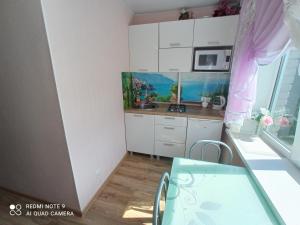 una pequeña cocina con armarios blancos y una mesa de cristal en Perfect Studio in Narva center, en Narva