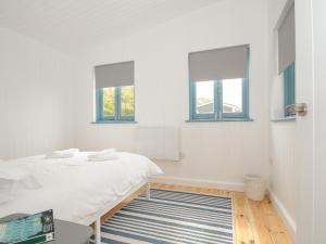 a white bedroom with a bed and two windows at Solana in Torpoint