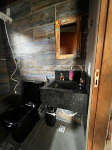 a bathroom with a black toilet and a sink at Recanto na Serra Bananeiras in Bananeiras