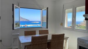 a kitchen with a table with chairs and a view of the ocean at Locals Apartment Karpathos in Karpathos Town +5 photos