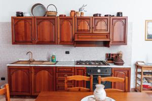 a kitchen with wooden cabinets and a table with chairs at Villa Maria in Sanarica