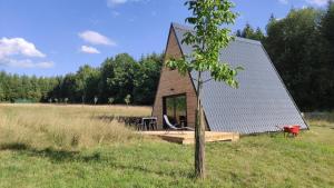 La maison en A في Meix-devant-Virton: كابينة صغيرة في حقل به شجرة