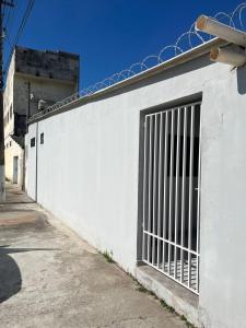 a white wall with a gate on the side of it at Casa do Marquinho in Aparecida