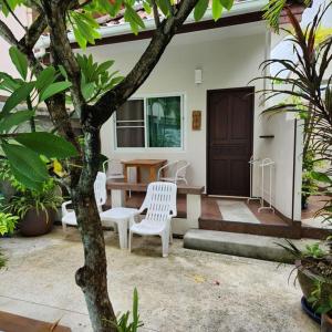 a patio with white chairs and a table and a door at Bungalows Musch Kamala Phuket in Kamala Beach