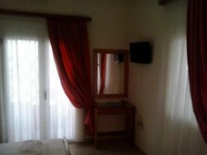 a bedroom with red curtains and a mirror and a window at Gradma Katina in Platanias