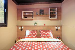 a small bedroom with a bed with red pillows at Huttopia Arcachon in Arcachon