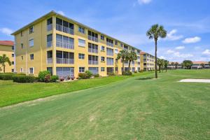 a large yellow apartment building with a green yard at Elegant Naples Condo with Golf View and Community Pool in Naples