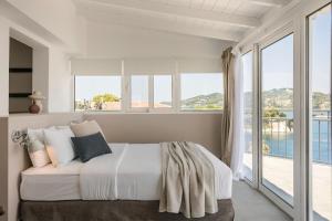 a bedroom with a bed and large windows at The Rock Suites in Skiathos +20 photos