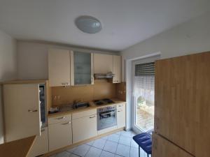 uma pequena cozinha com armários brancos e uma janela em Ferienwohnung Unterneukirchen mit Garten-Terrasse em Unterneukirchen