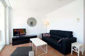 een woonkamer met een zwarte bank en een tv bij Escorpora in L'Estartit