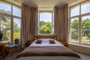 a bedroom with a large bed and large windows at Hôtel et SPA du Château in Lagord +28 photos