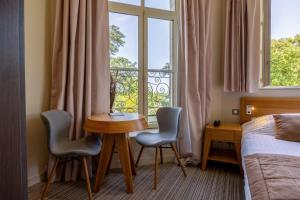 a room with a table and two chairs and a window at Hôtel et SPA du Château in Lagord