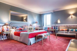 a bedroom with a bed and a couch in a room at Le Manoir De La Poterie & Spa in Cricquebœuf