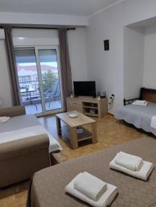 パレオ・ティフリキにあるVasilikiのベッド2台、テレビ、バルコニーが備わる客室です。