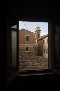 una ventana con vistas a un edificio de ladrillo y a una torre del reloj en Nel tranquillo centro d'Isola, en Isola di Fano