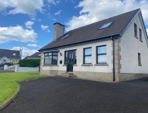 a white house with a black door and windows at Holiday Home in Ballycastle - Fáinne na Cairde in Ballycastle