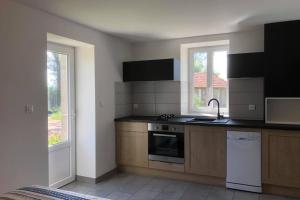 a kitchen with a stove and a sink and two windows at Studio l'Eau de Bel Air in Droiturier