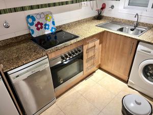 cocina con fogones horno de arriba junto a un fregadero en Apartamentos Deluxe Marina Dor, en Oropesa del Mar