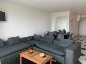 ein Wohnzimmer mit einem blauen Sofa und einem Tisch in der Unterkunft Arcadia appart face mer 7 pers in Le Touquet-Paris-Plage