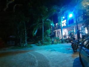 a street at night with cars parked in front of a building at New Sunrise Hotel in Batticaloa